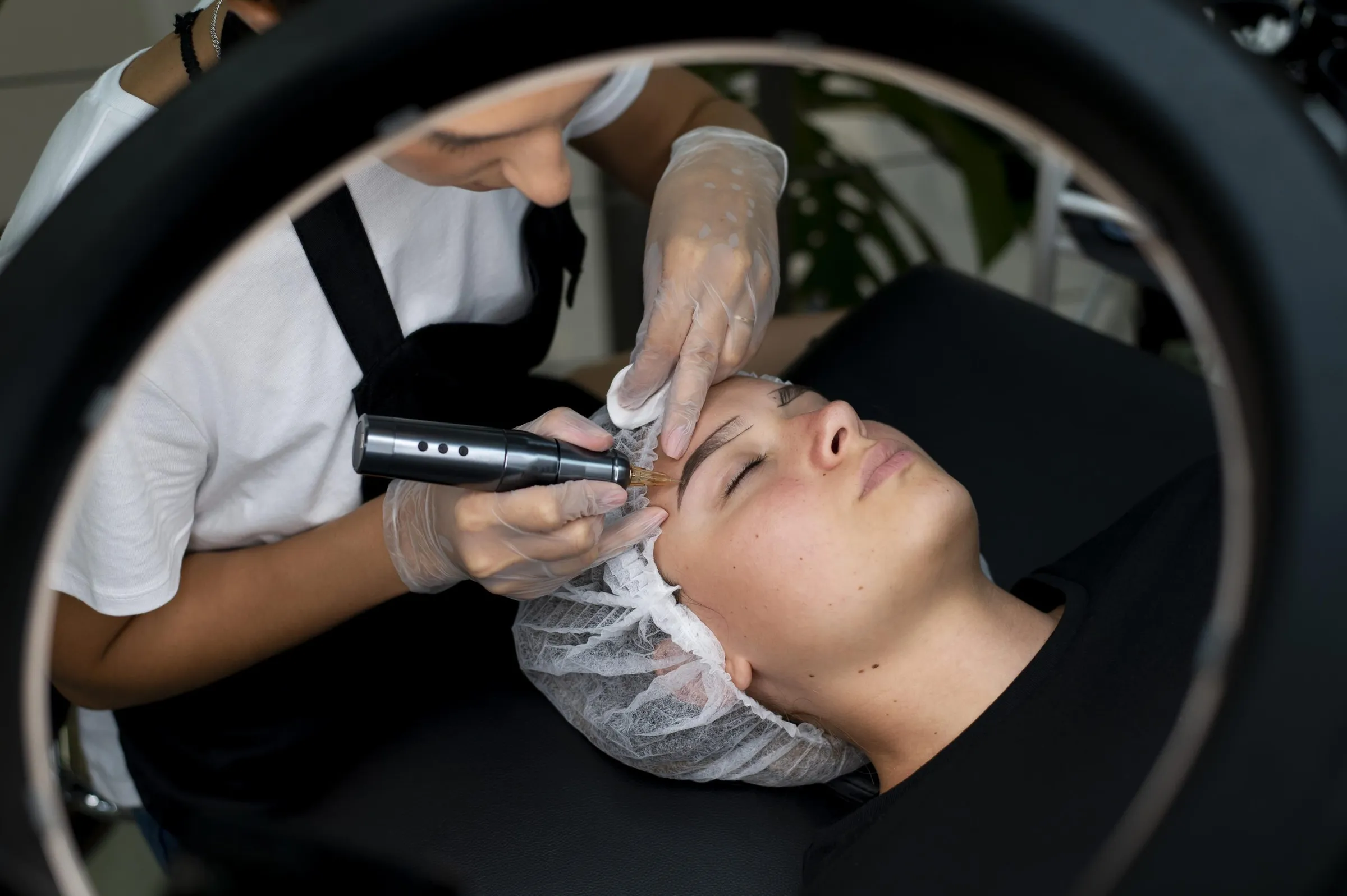 A permanent makeup artist mapping a client’s brows with thread